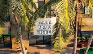 un panneau d'hôtel avec des palmiers devant un bâtiment dans l'établissement Seara Praia Hotel, à Fortaleza