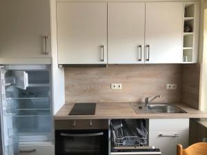 a kitchen with white cabinets and a sink and an open refrigerator at Gemütliche Wohnung 4 mit Balkon zu Fuß zum Strand & Hafen Bensersiel in Bensersiel