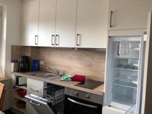 a kitchen with a sink and an open refrigerator at Wohnung 3 mit Terrasse Haus Annegrete in Bensersiel +12 photos