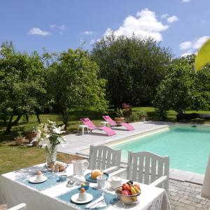 uma mesa com uma tigela de fruta ao lado de uma piscina em Au Logis de la Mongie em Soullans