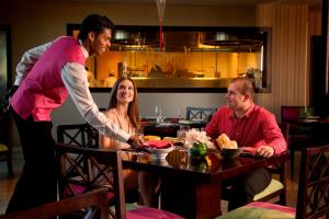 a man serving a woman at a table in a restaurant at Yas Island Rotana Abu Dhabi in Abu Dhabi