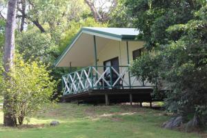 a house with a porch in the middle of trees at Capricorn Caves in Rockhampton