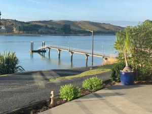 a dock on a body of water with a palm tree at Beach Lane Apartment in Whangarei
