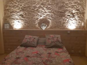 a bed with two pillows and a wall with lights at Suite Privée Bed and Breakfast in Nîmes