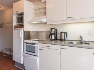 a kitchen with white cabinets and a sink and a refrigerator at Holiday home Fanø LIII in Fanø