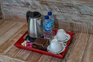 a tray with a tea kettle and two bottles of water at Helly's Secret Garden Cottage in Nusa Lembongan