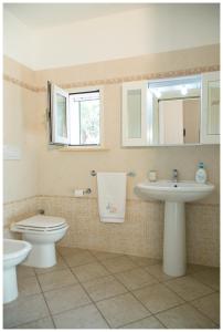 ein Badezimmer mit einem Waschbecken, einem WC und einem Spiegel in der Unterkunft Appartamenti Corciulo in Salve