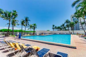 a large swimming pool with chairs and palm trees at Ocean Front Casablanca Studios with FULL KITCHENS & Beach access By BL Rentals in Miami Beach