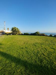 un campo de hierba verde con el océano en el fondo en Ocean front apartment., en San Antonio del Mar