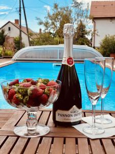 eine Flasche Champagner und eine Schale Erdbeeren auf dem Tisch in der Unterkunft Barackvirág Apartmanház in Tihany