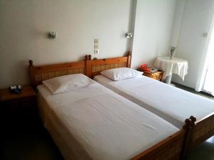 two twin beds in a bedroom with a table at Hotel Rena in Agios Kirykos