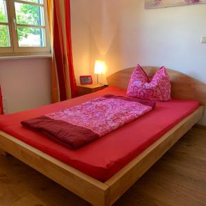 uma cama com um cobertor vermelho e almofadas em Apartment with a stunning view of the alps - Wohnung mit atemberaubenden Blick auf die Alpen em Fischbachau