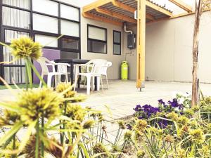 a patio with white chairs and a table and flowers at The Cabin in Swakopmund