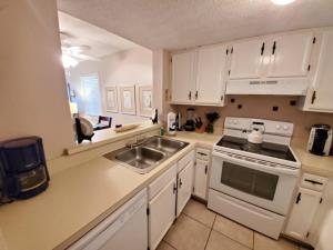 a kitchen with white cabinets and a sink and a stove at St, Augustine Ocean And Racquet 2204 Condo in St. Augustine