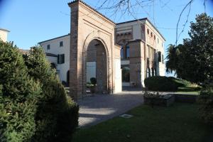 a large brick building with an arch in a yard at Villa Santa Maria dell'Arco - Centro Oreb in Cazzago San Martino