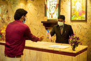 un homme portant un masque donnant à un homme une brosse à dents dans l'établissement Hotel Ragavendra Rameswaram, à Rameswaram