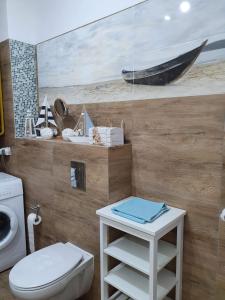 a bathroom with a toilet and a painting of a boat at Apartament Bursztyn in Pobierowo