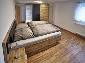 een groot bed in een slaapkamer met een houten vloer bij Albglück in Gammertingen