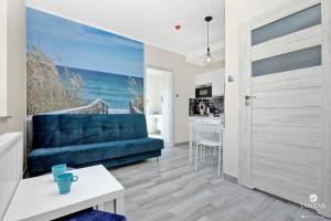 sala de estar con sofá azul y cocina en Jantar Apartamenty - APARTAMENTY KLARA en Grzybowo