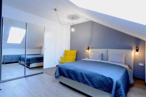 a bedroom with a blue bed and a yellow chair at Marmot apartment up & down in Poiana Brasov