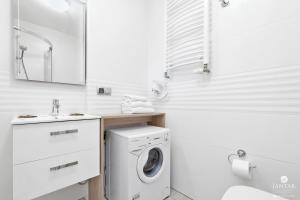 baño blanco con lavadora y lavamanos en Jantar Apartamenty - APARTAMENTY KLARA en Grzybowo