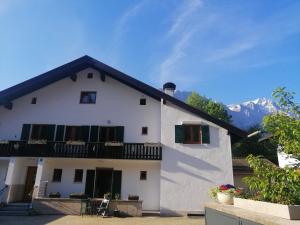 a white house with a balcony and mountains in the background at Ferienwohnung Jubiläumsgrat in Grainau