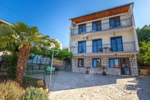 a building with a palm tree in front of it at Apartmani Pilaš in Dramalj