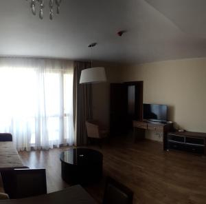 Una sala de estar con un sofá y un televisor. en Apart Hotel Golden Line, private property rm 214, en Golden Sands