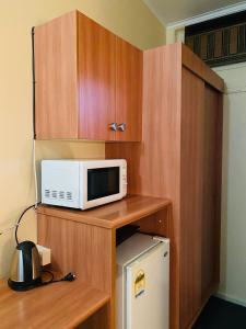 a microwave sitting on a shelf next to a refrigerator at County Lodge Motor Inn in West Wyalong