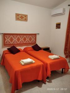 2 camas en una habitación con sábanas de color naranja en B&B San Francesco, en Oliena