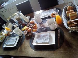 einen Tisch mit Teller mit Lebensmitteln und Gläsern Orangensaft in der Unterkunft La Hulotte au Col Haut in Audrehem