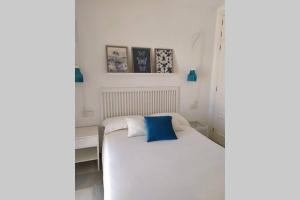 a bedroom with a white bed with a blue pillow at apartamento Costa Sancti-Petri La Barrosa Chiclana in Chiclana de la Frontera