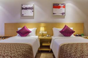 Novo Hotel Chongqing في تشونغتشينغ: سريرين في غرفة الفندق مع وسائد أرجوانية