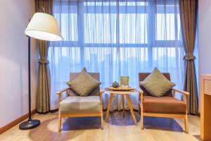 a living room with two chairs and a table and a large window at Novo Hotel Chongqing in Chongqing