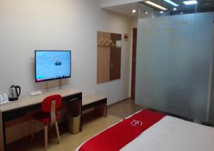 a room with a bed and a desk with a television at Thank Inn Chain Hotel Taizhou Dainan Guzhuang Village Bus Station in Taizhou