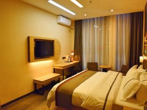 a hotel room with a bed and a desk and a television at Thank Inn Chain Hotel Huaihua Tongdao Bus Station in Tongdao