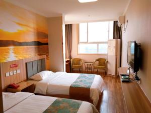 a hotel room with two beds and a flat screen tv at JUN Hotels Shandong Tai'an Daiyue District Tai'an High Speed Railway Station Store in Tai'an