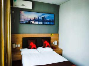 - une chambre avec un lit et une télévision murale dans l'établissement JUN Hotels Lu'an Huoshan County Huayuan Road, à Lu'an