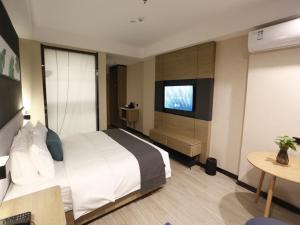 ein Hotelzimmer mit einem Bett und einem TV in der Unterkunft Up and In Kashgar Xiyu Avenue Food Street in Kashgar