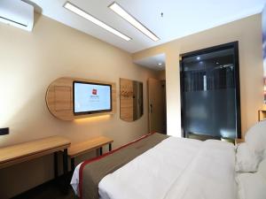 um quarto com uma cama e uma televisão na parede em Thank Inn Chain Hotel Anhui Bengbu Huaiyuan County Huarun Suguo Store em Wuchazhen