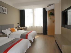 um quarto de hotel com duas camas e uma televisão de ecrã plano em JUN Hotels Shandong Liaocheng Eco-Tech Development Zone Contmporary International Plaza em Liaocheng