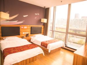 una camera d'albergo con due letti e una grande finestra di Thank Inn Chain Hotel He'nan Zhengzhou Zhengdong New District East Staiton a Zhengzhou