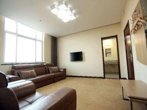uma sala de estar com um sofá e uma televisão de ecrã plano em JUN Hotels Hebei Shijiazhuang Lingshou Zhongtian Commercial Building em Shijiazhuang