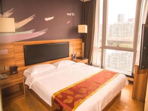 - une chambre avec un grand lit et une grande fenêtre dans l'établissement Thank Inn Chain Hotel He'nan Zhengzhou Zhengdong New District East Staiton, à Zhengzhou