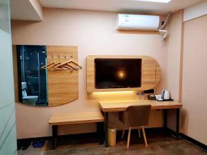 une pièce avec un bureau avec une télévision et un ordinateur dans l'établissement Thank Inn Chain Hoteln Jiangsu Suzhou Kunshan Lujia Town Youyi Road, à Suzhou
