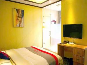 a bedroom with a bed and a desk with a television at JUN Hotels Sichuan Chengdu Jianyang Jiancheng Town Jianshe Road in Jianyang