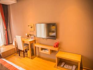Zimmer mit einem Schreibtisch und einem TV an der Wand in der Unterkunft JUN Hotels Yunnan Kunming Wuhua District Changyuan Middle Road in Kunming