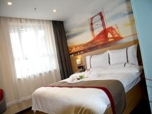 a bedroom with a large bed with a painting on the wall at Thank Inn Chain Hotel Aksu Juche Tianwu Plaza in Kuqa