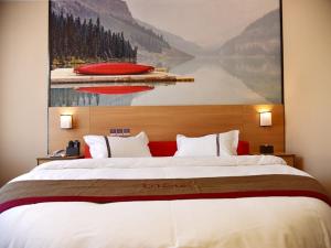 a bedroom with a large bed with a painting on the wall at Thank Inn Chain Hotel Guizhou Tongren Bijiang District High-speed Railway Station Qingshui Avenue Store in Tongren