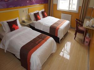 um quarto de hotel com duas camas e uma mesa e cadeiras em JUN Hotels Jinan Tianqiao District Railway Station Square em Jinan